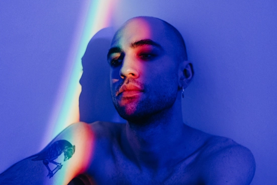 Rapaz sentado contra a parede com um feixe luminoso em seu rosto