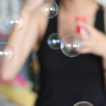 Qual o significado de usar preto no ano novo? preto no ano novo mulher de preto soprando bolhas de sabao