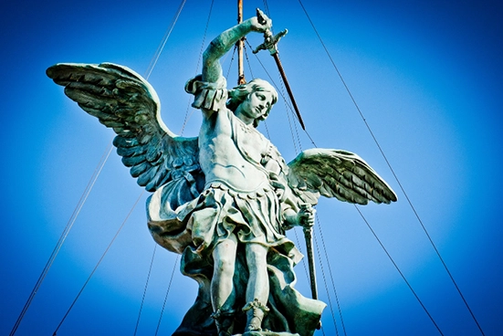 Estátua do Anjo Miguel empunhando espada sob céu azul.