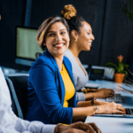 Quais os melhores amuletos contra inveja no trabalho? amuletos contra inveja no trabalho mulher sorrindo no escritório