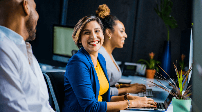 Quais os melhores amuletos contra inveja no trabalho? amuletos contra inveja no trabalho mulher sorrindo no escritório