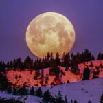 Super Lua 2023: Renovações, Passagem e Autoconhecimento Super lua sob uma montanha em frente a um céu arroxeado