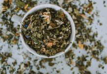 Herbalismo: explorando o poder das ervas e suas aplicações práticas Imagem de uma xícara branca com ervas e flores secas picadas