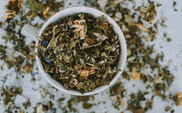 Herbalismo: explorando o poder das ervas e suas aplicações práticas Imagem de uma xícara branca com ervas e flores secas picadas