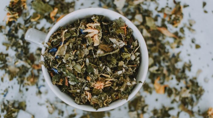 Herbalismo: explorando o poder das ervas e suas aplicações práticas Imagem de uma xícara branca com ervas e flores secas picadas