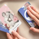 O que esperar da sua primeira consulta de Tarot online A imagem mostra as mãos de alguém manipulando um Tarot com o tema da iQuilibrio