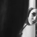 Desvendando a Sombra: como Oráculos podem iluminar aspectos inconscientes Mulher se olhando no espelho, em ambiente sombrio