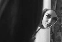 Desvendando a Sombra: como Oráculos podem iluminar aspectos inconscientes Mulher se olhando no espelho, em ambiente sombrio