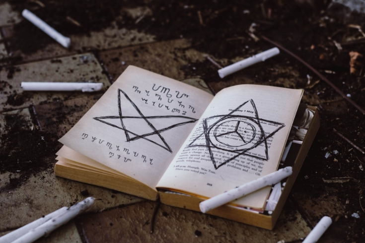 Livro antigo, com pentagrama invertido na página esquerda, hexagrama na direita.