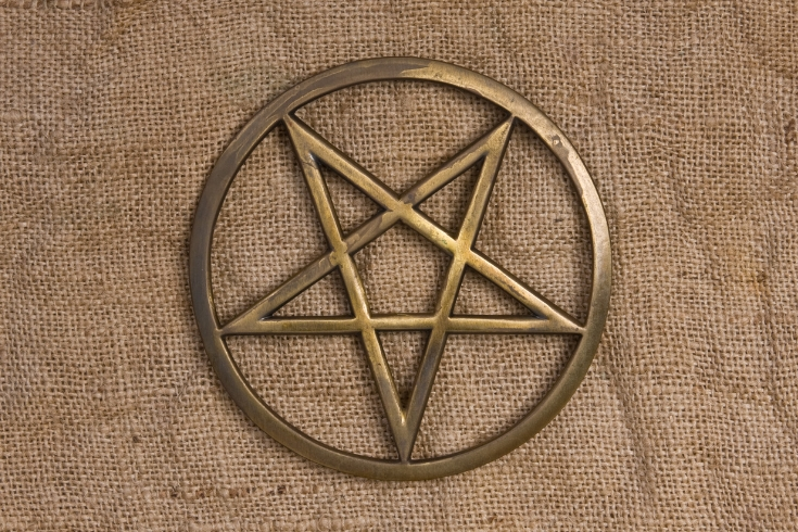 Um pentagrama de metal, dentro de um círculo (pentáculo), com uma ponta para baixo e duas para cima.