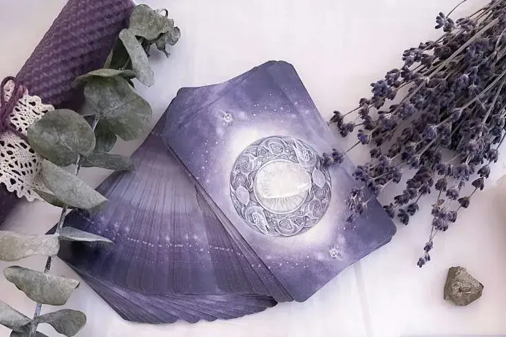 Cartas de Tarot dispostas sobre mesa branca, com ervas e cristais