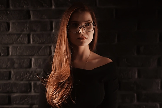 Mulher misteriosa, com o cabelo sobre os ombros, na penumbra.