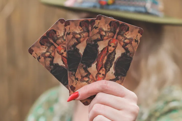 Mão feminina segurando cartas do baralho cigano em formato de leque