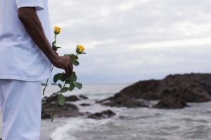 Pessoa vestida de branco atirando rosas ao mar